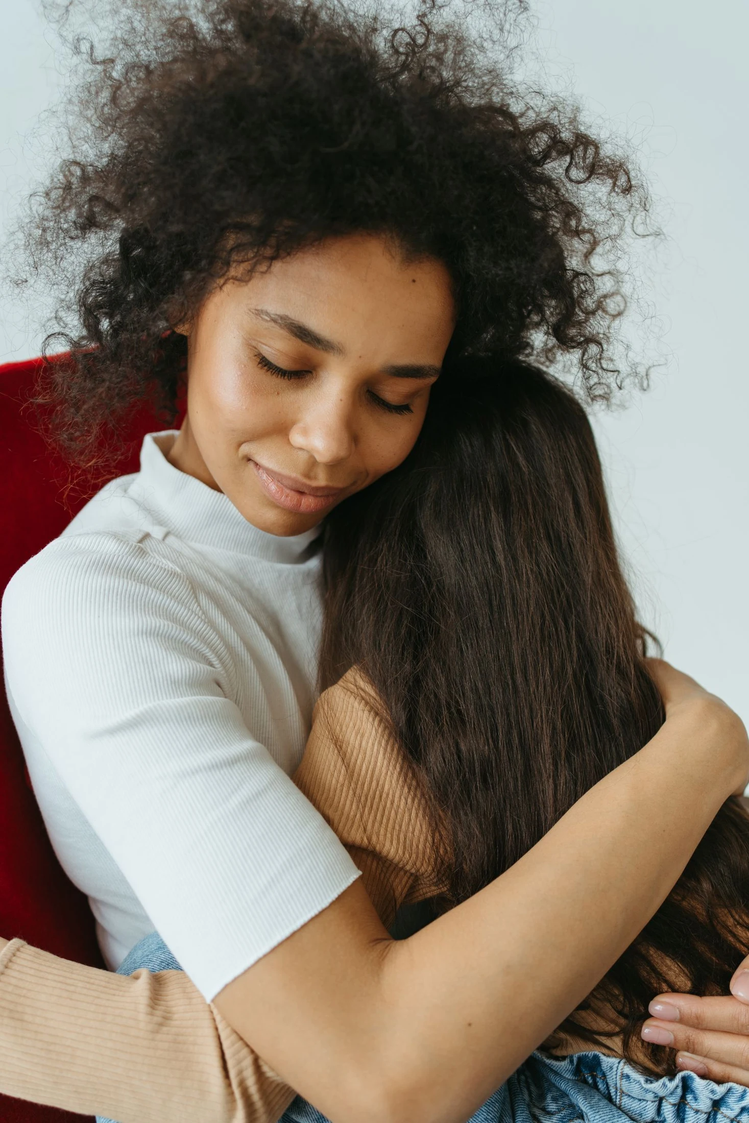 A Black mother embracing her daughter